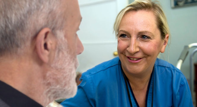 An older man chatting with a nurse